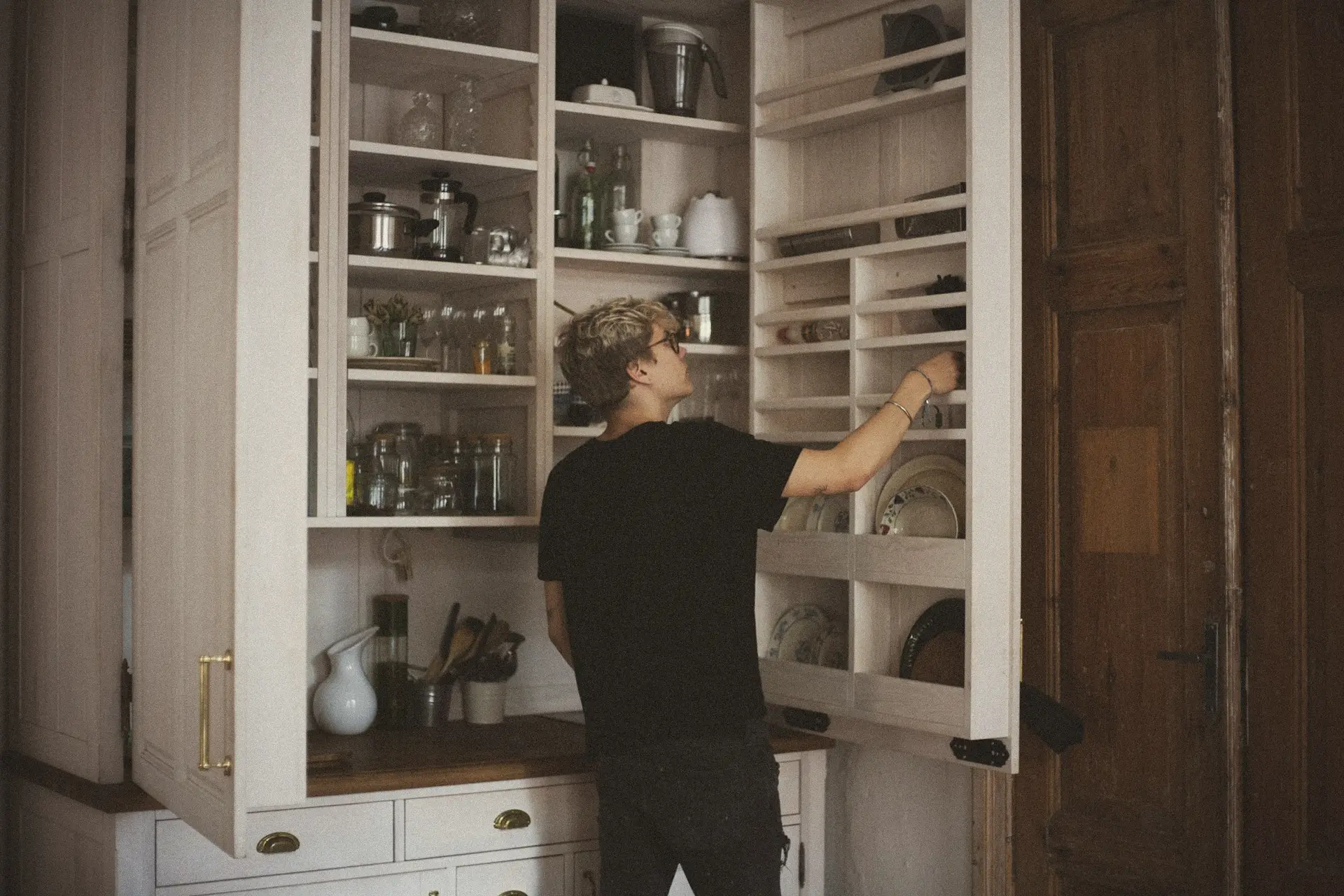 man standing near cabinet reaching plate